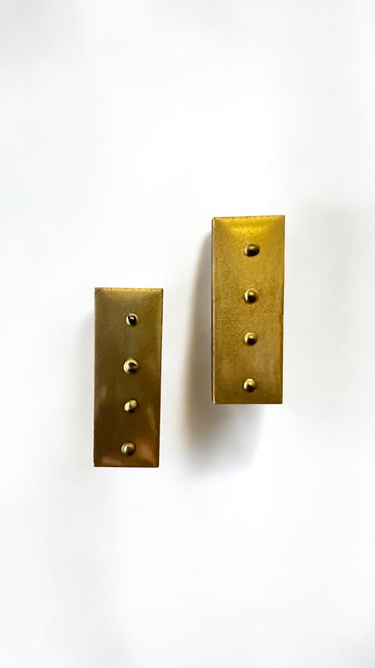 Two brass rectangular plates with holes on a white background